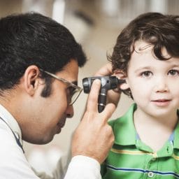 Image of a doctor checking on a little boy's ear
