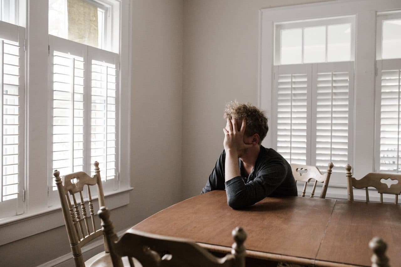 Sad looking man sitting at kitchen table.