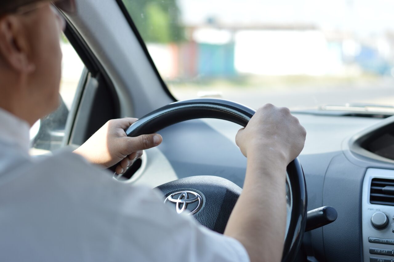 Close-up of a man's hands on the steering wheel while driving.