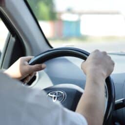 Close-up of a man's hands on the steering wheel while driving.