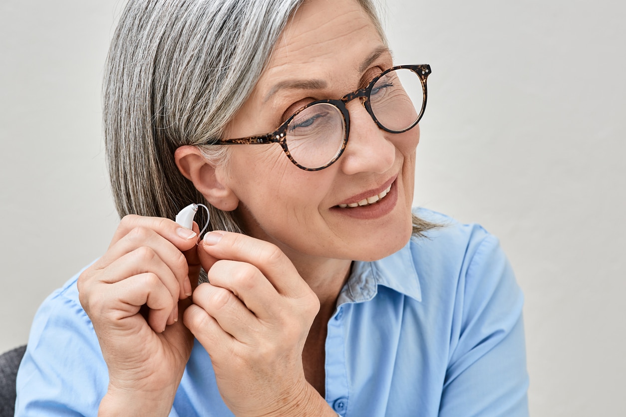 Smiling woman putting in a hearing aid